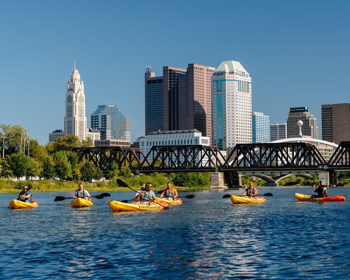 kayakers on water with Columbus skyline in the background
